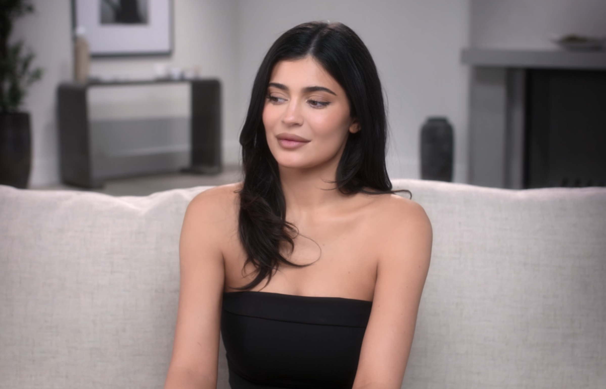 Close-up of Kylie sitting and wearing a strapless top