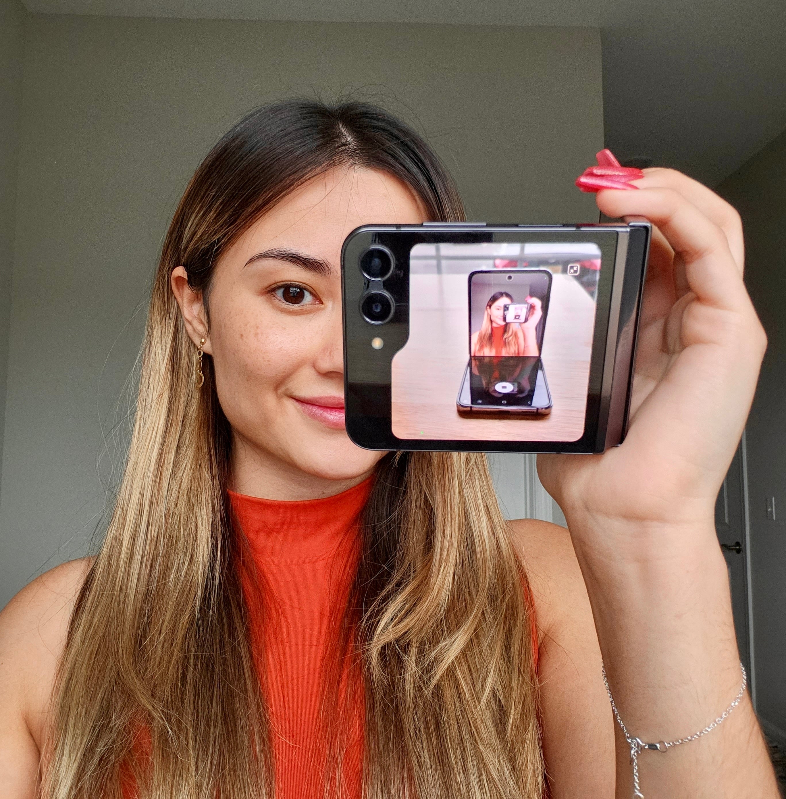 author holding Flip 5 folded sideways similar to a camcorder, with the cover screen viewfinder showing a picture of the Flip 4