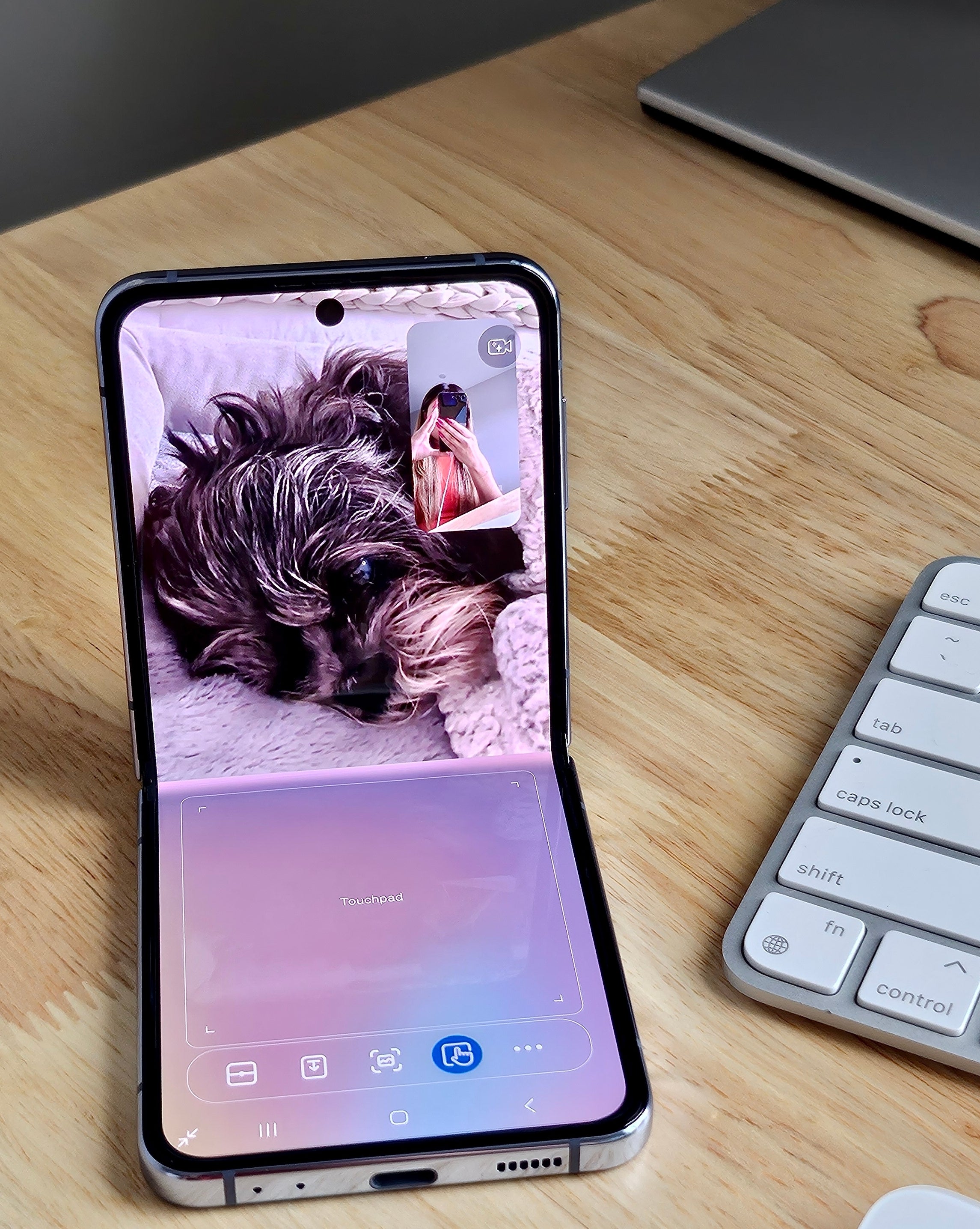 Flip 4 folded at roughly 90 degrees while opened to a video call on the top half and a touchpad with controls on the bottom half of the screen