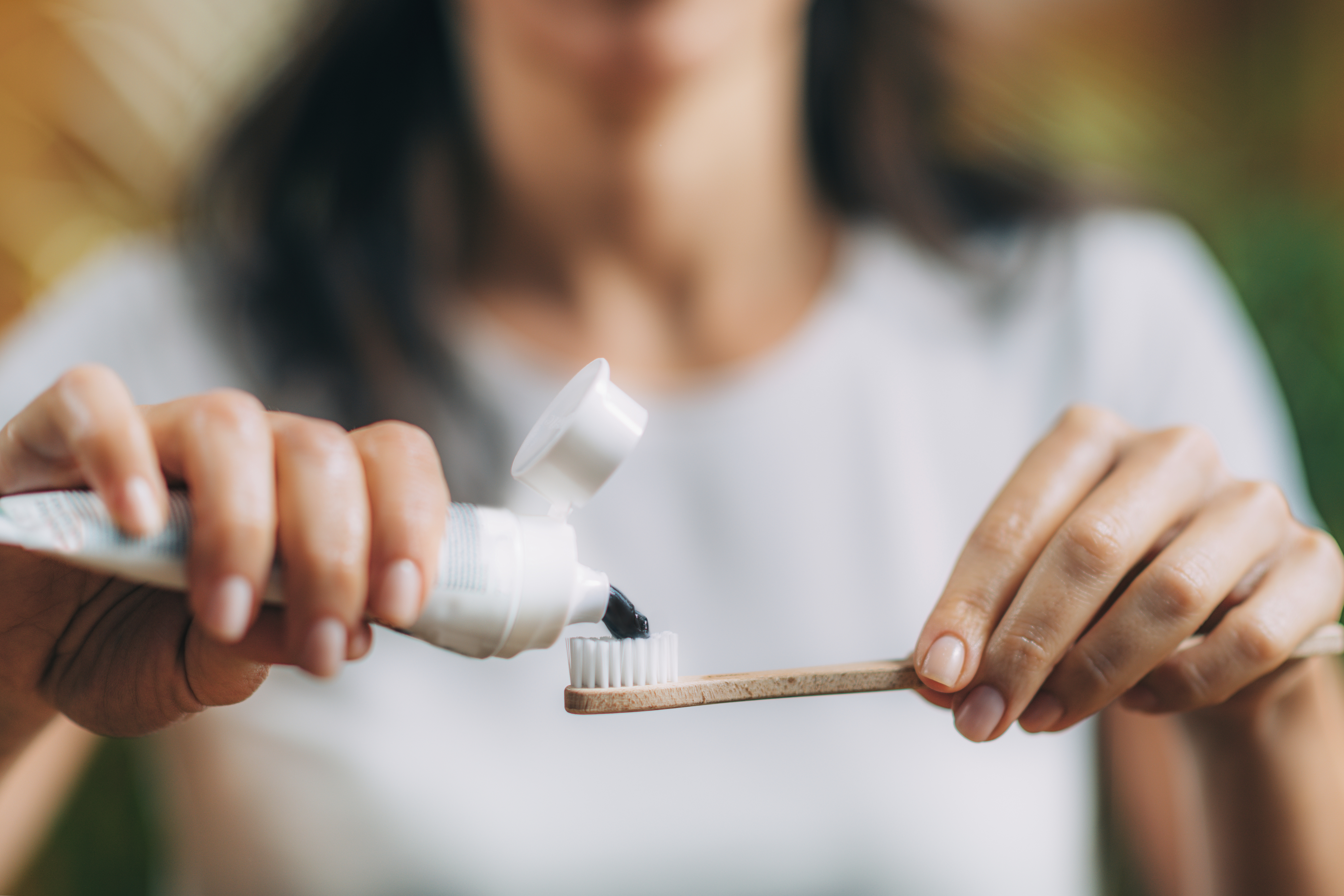 a person putting toothpaste on top of a toothbrush