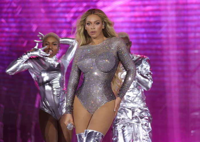 Beyoncé performing on stage in a glittery bodysuit with backup dancers in silver outfits