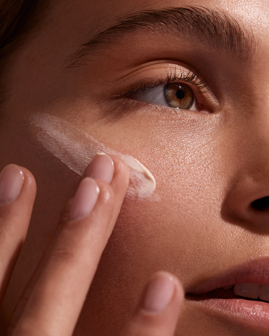 Close-up of a person applying cream under their eye