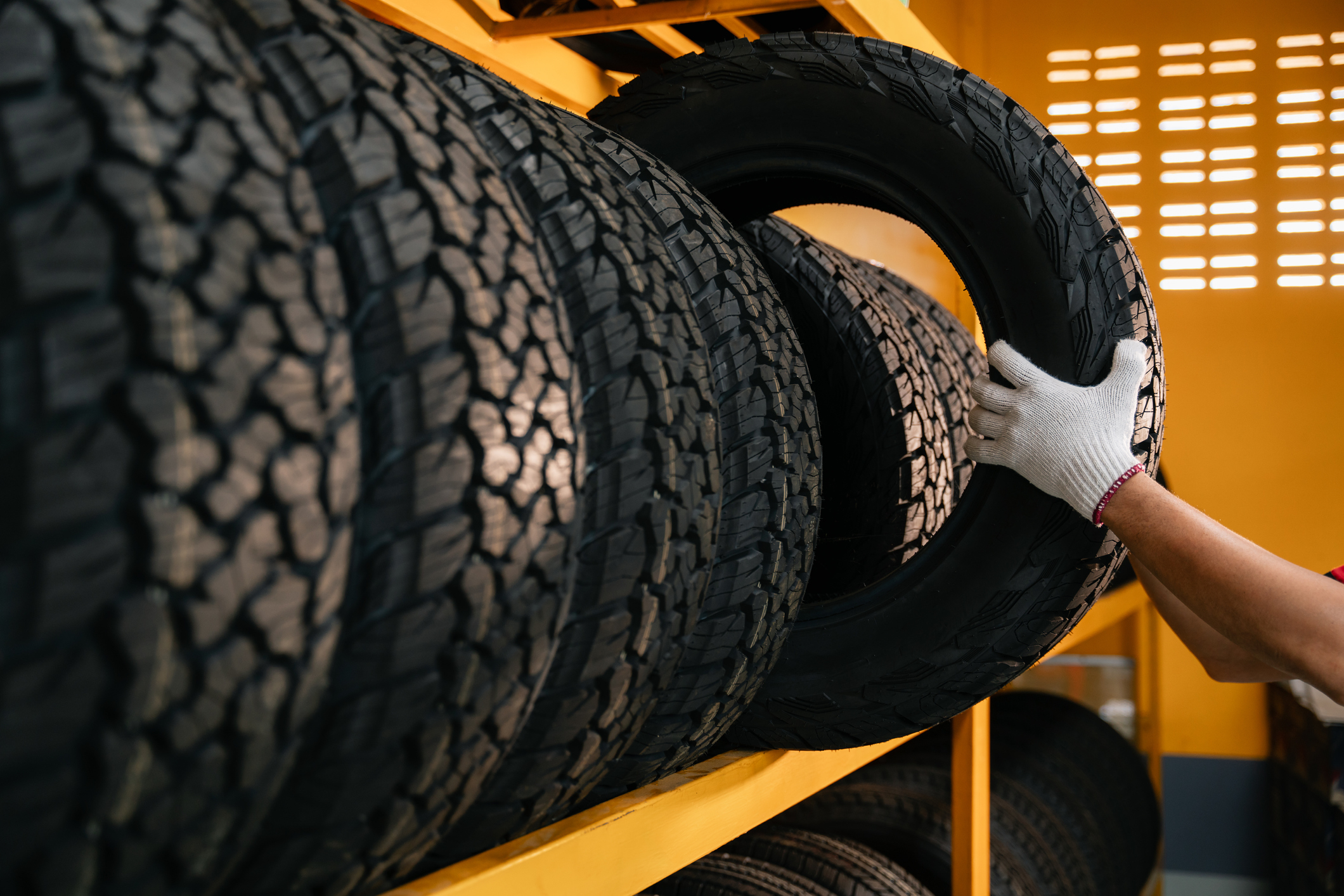 Person&#x27;s hand selecting a tire from a rack of various tires