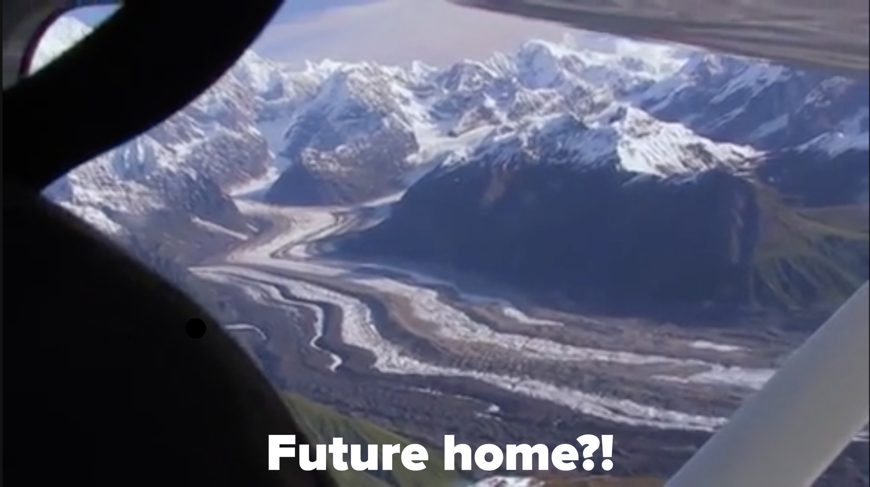 Aerial view of a glacier winding through mountains, seen from an airplane window