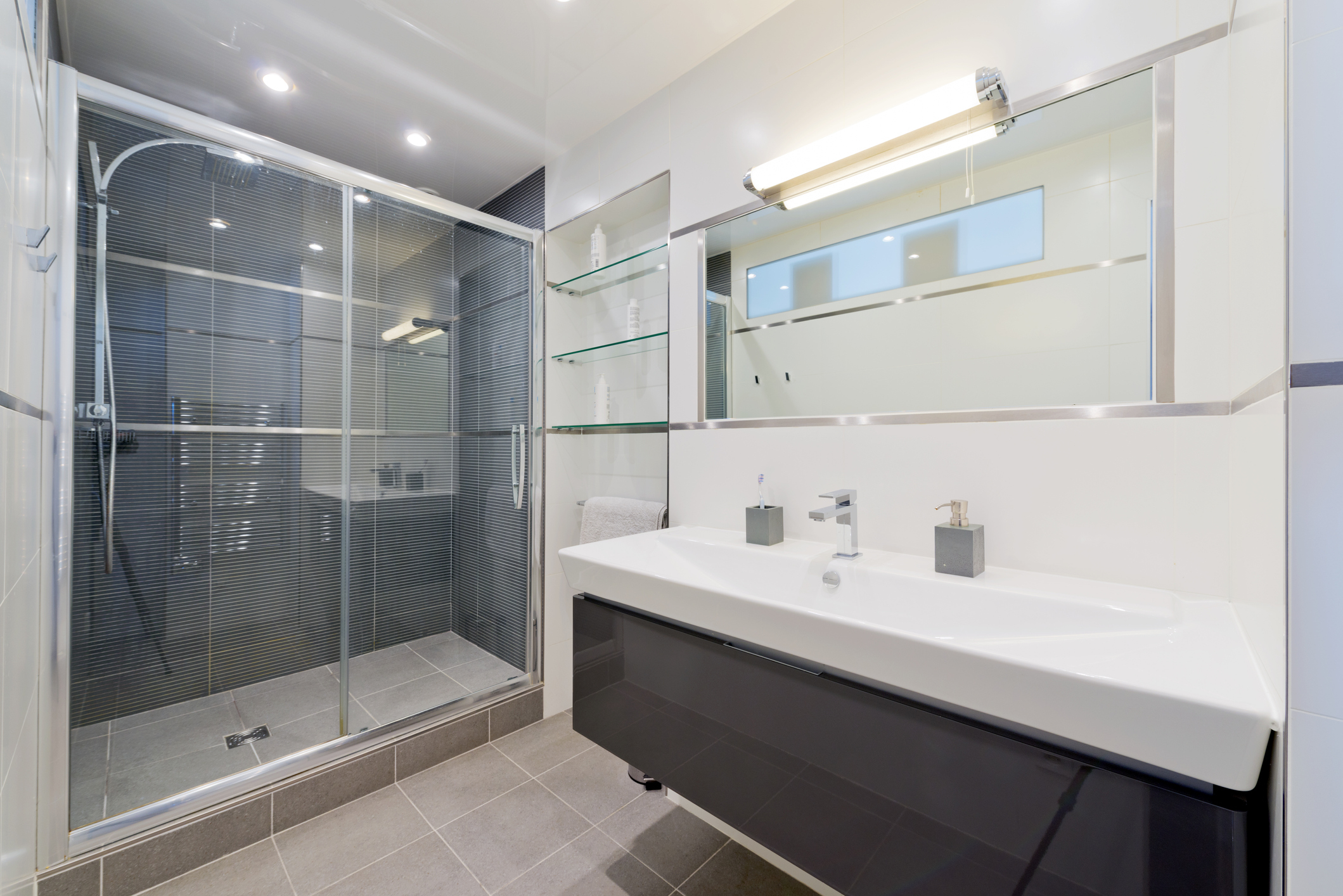 Modern bathroom with a walk-in shower, double vanity sink, and a large mirror