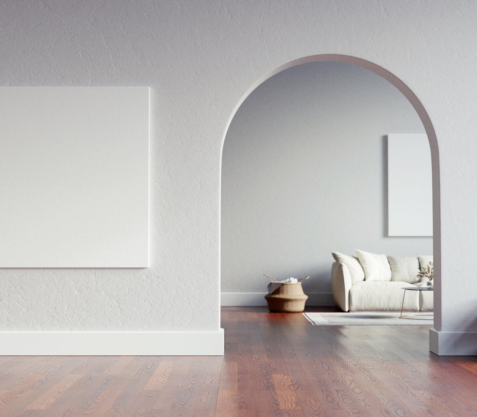 A minimalist room with an empty picture frame on the wall and a simple furnished living area through an archway
