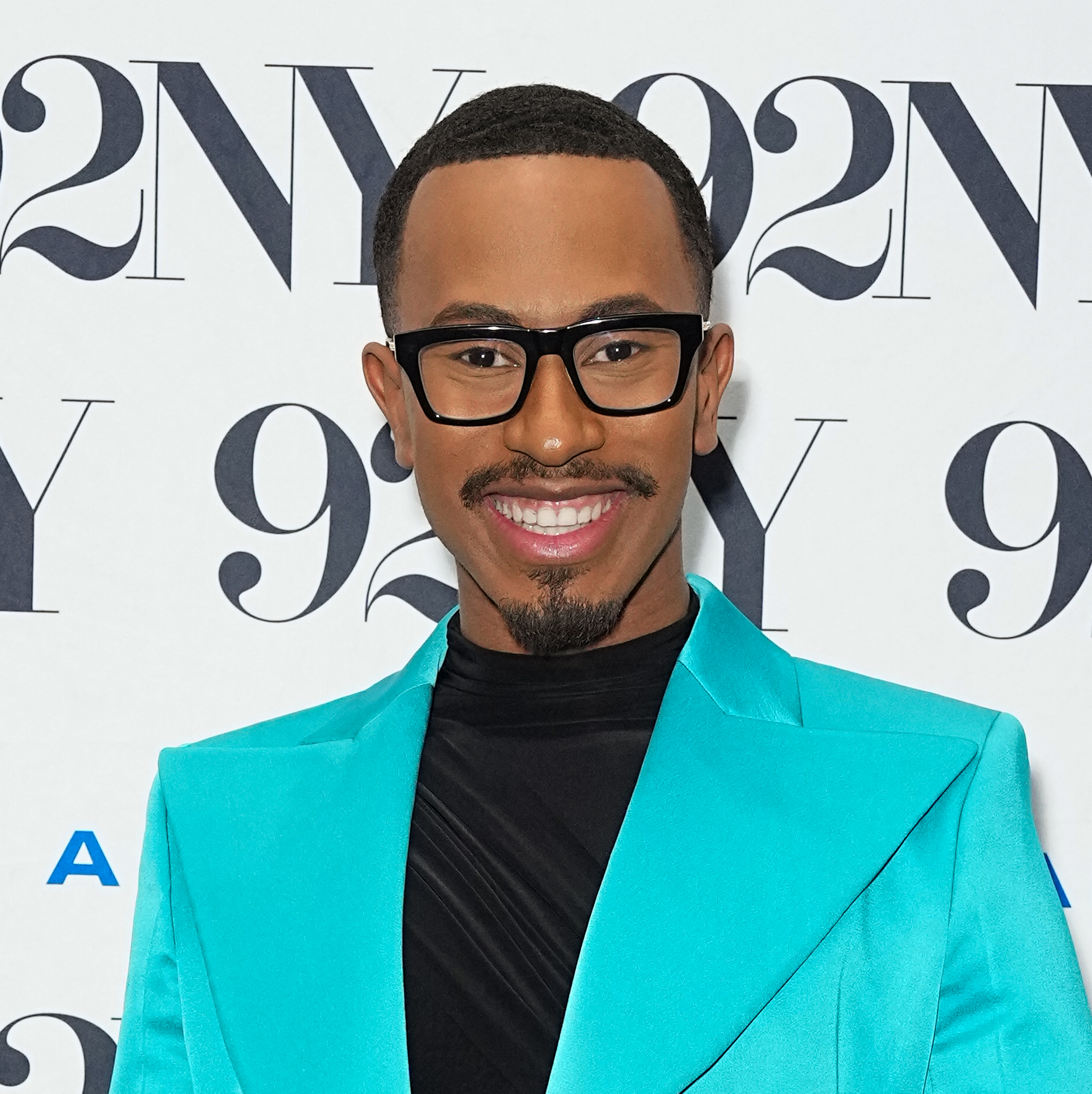 A closeup of Kalen in a blazer smiling at a media event