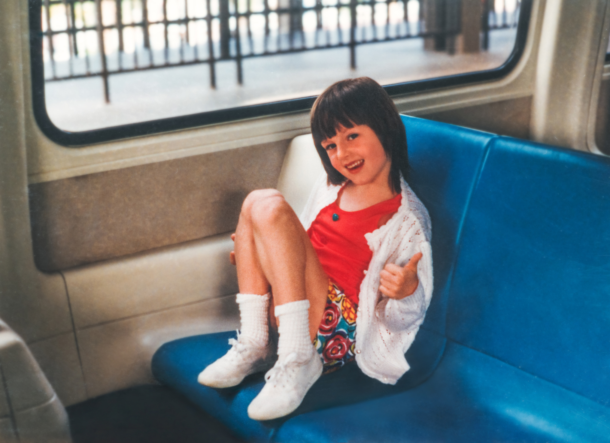 A little girl is seated on a bus