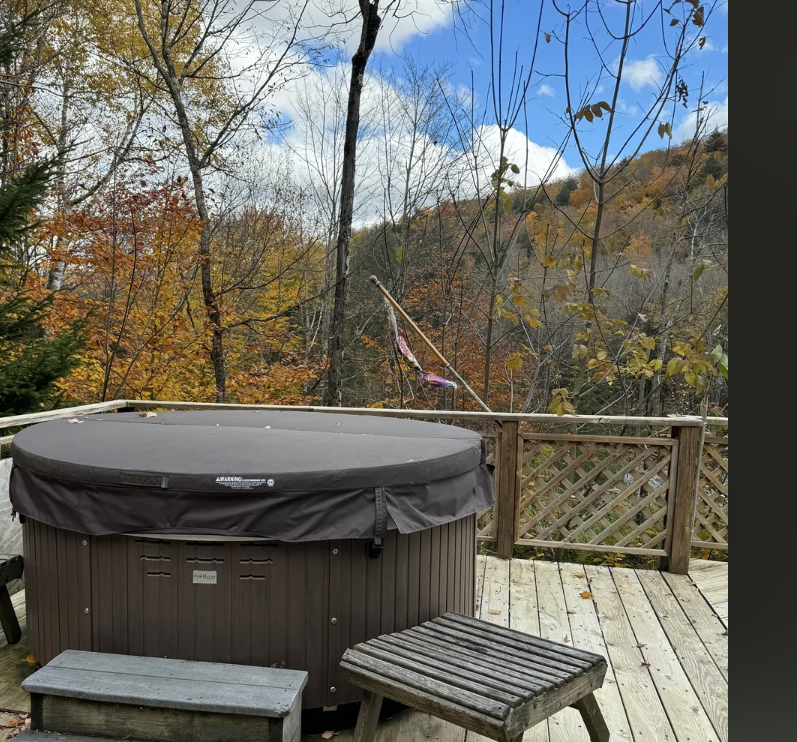 Backyard with a hot tub and wooden furniture amidst autumn trees