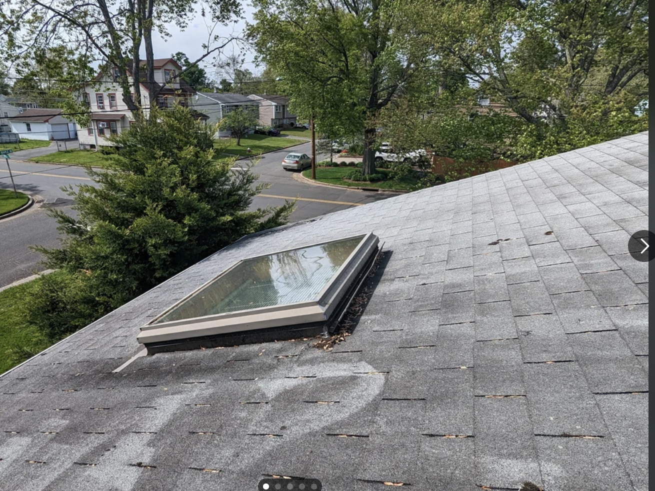 Skylight on a house roof with surrounding trees, viewed from an upper window