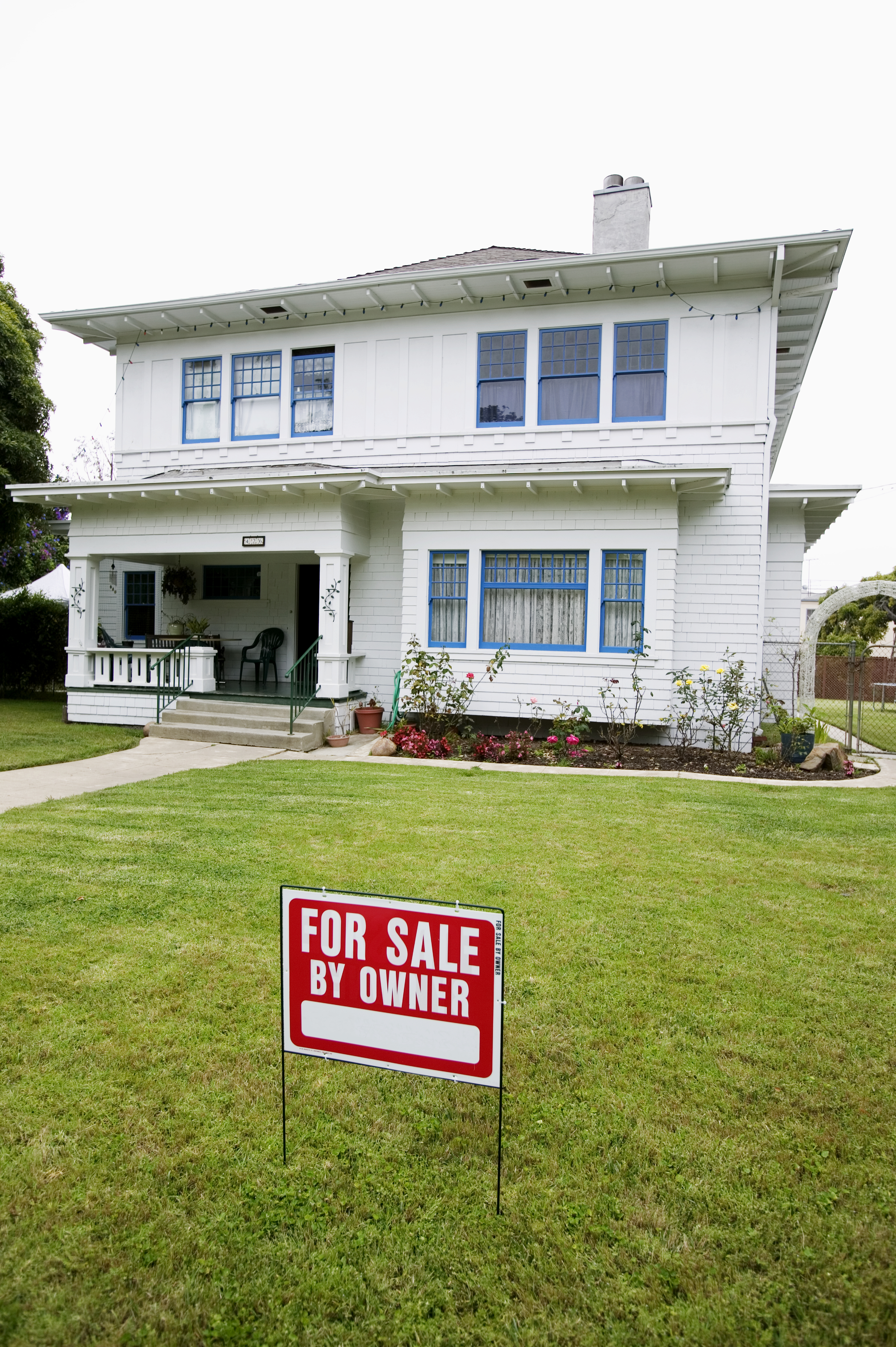 Two-story house with a &quot;For Sale By Owner&quot; sign on the front lawn