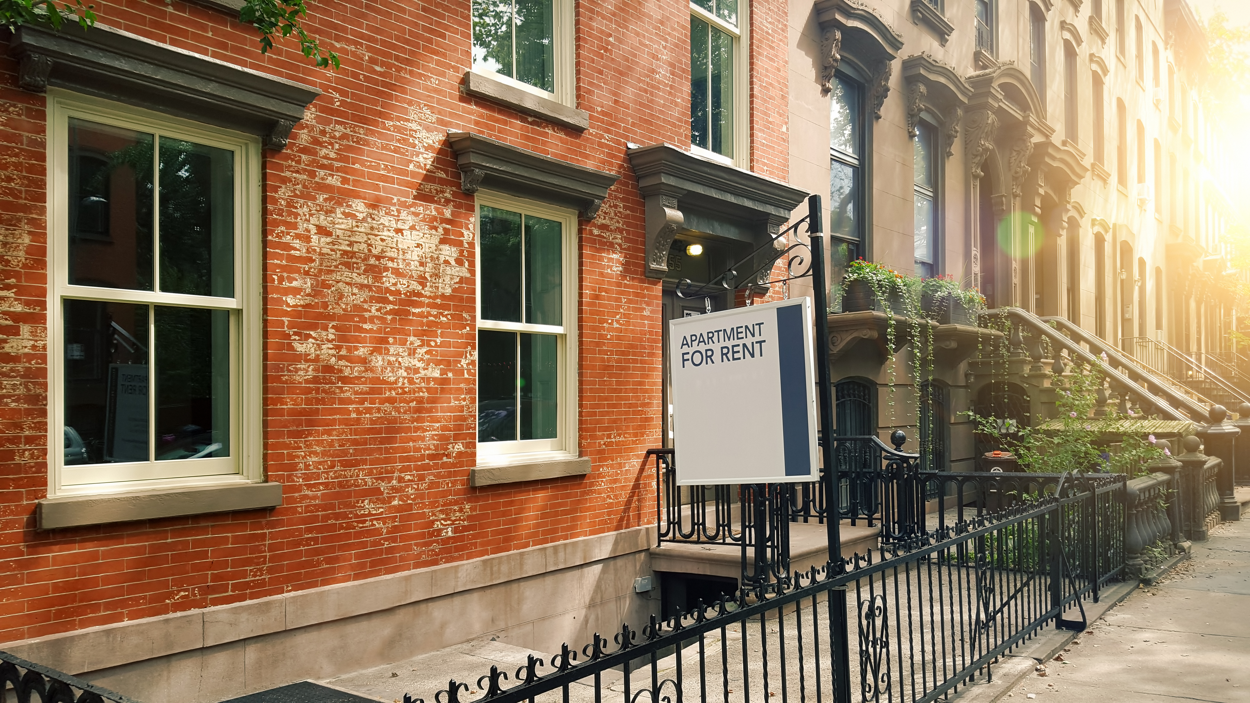 Brick building with an &quot;Apartment for Rent&quot; sign on the front stoop