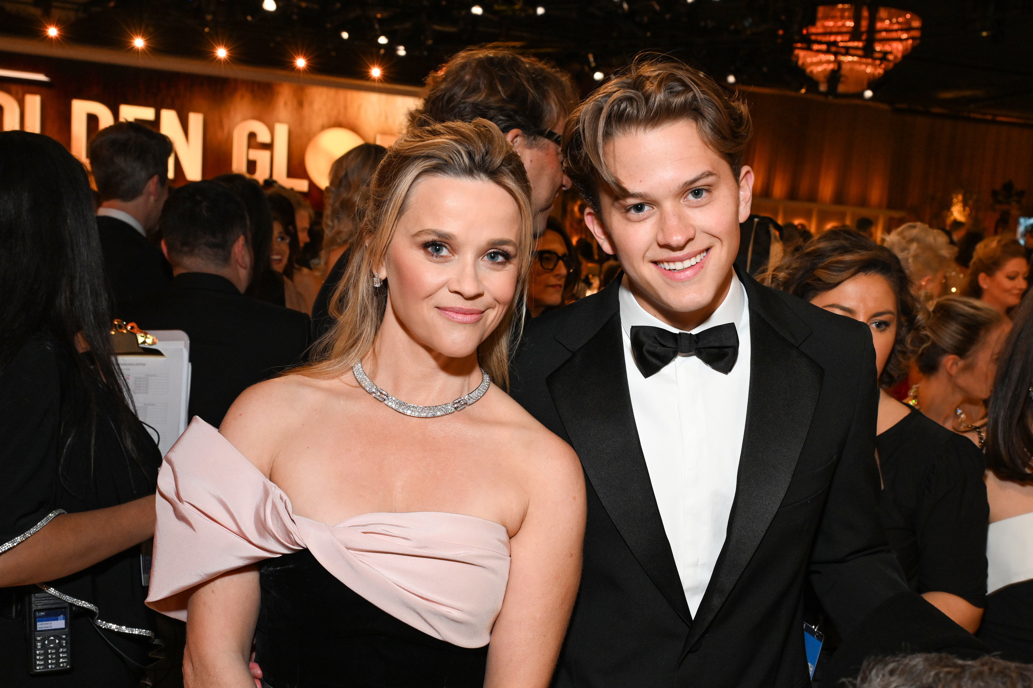 Reese and Deacon smiling at the camera, she in a strapless gown, he in a tuxedo