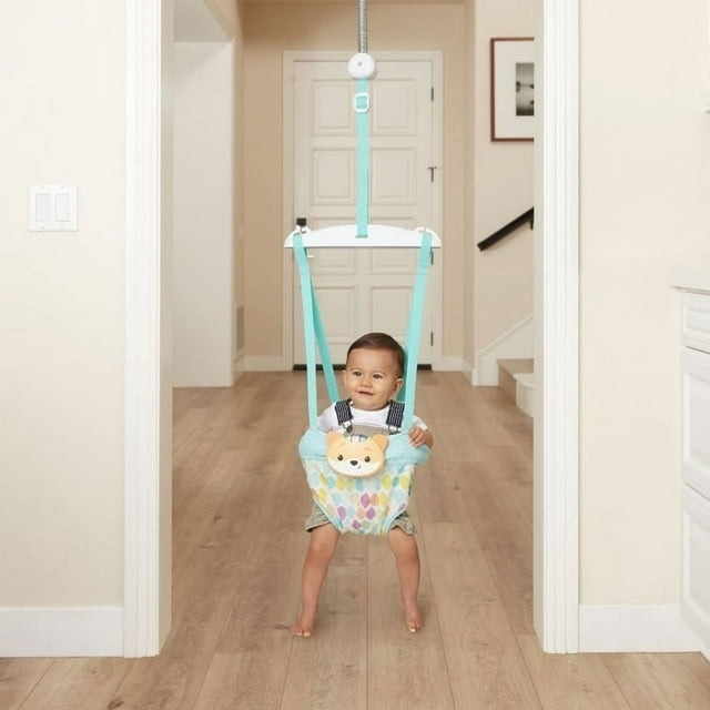 Toddler in a doorway jumper, smiling, wearing a romper with a bow tie