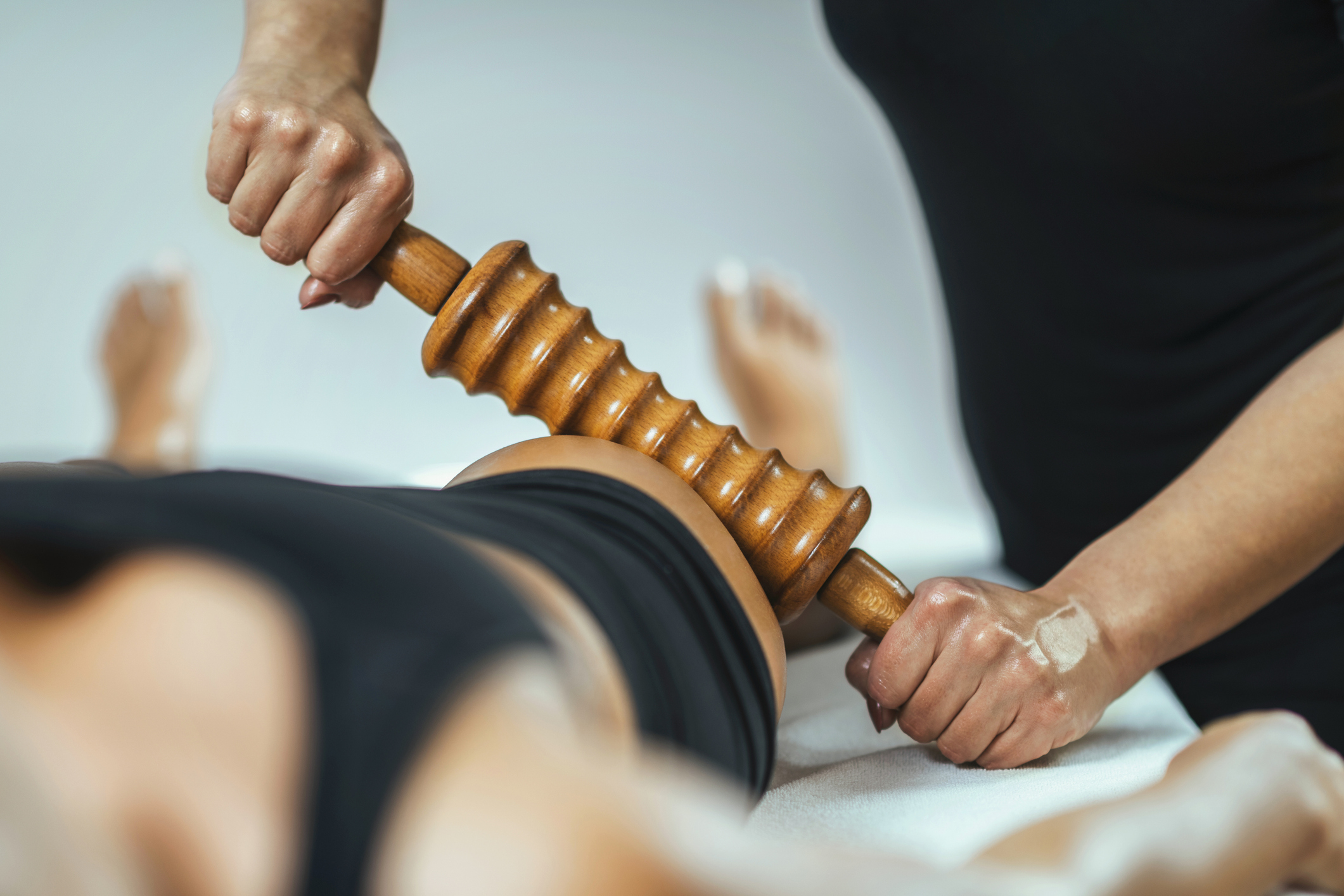 Person receives a back massage using a wooden tool