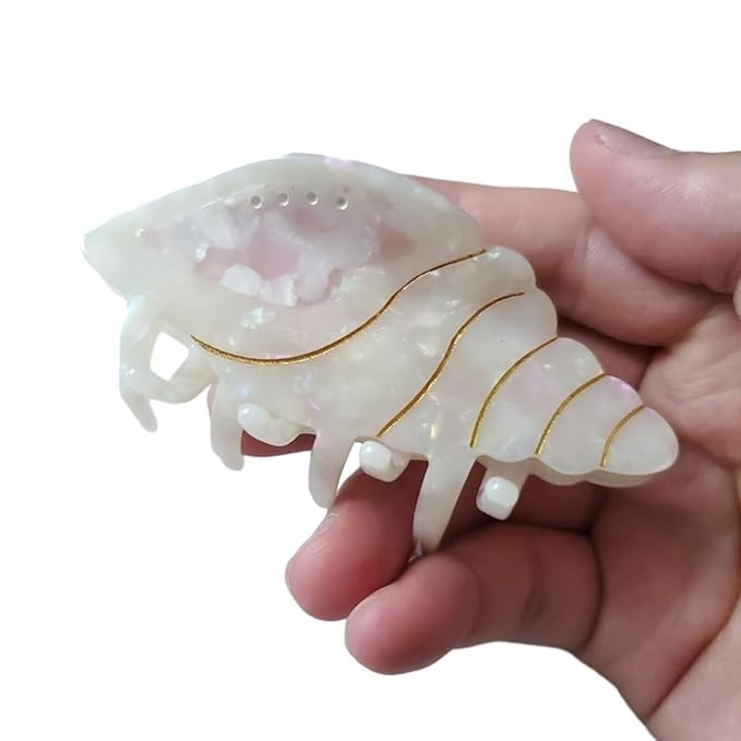 Hand holding a translucent hair claw accessory with gold accents