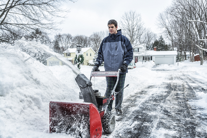 Person using a snowblower to clear a snowy driveway