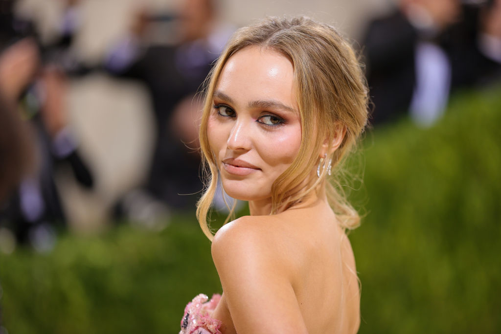 Celebrity at an event wearing a floral-embellished gown, smiling over her shoulder