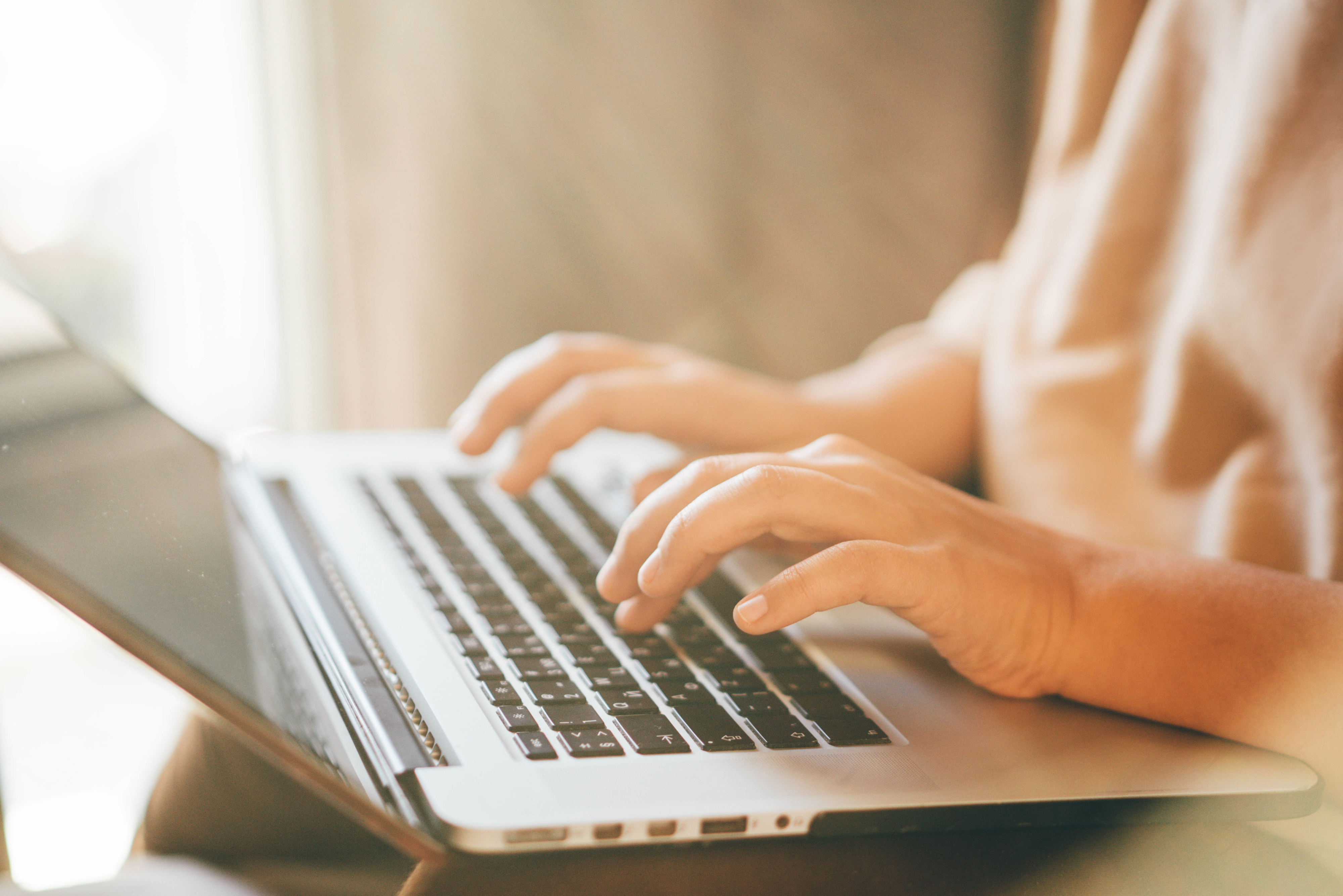 Close-up of a person&#x27;s hands typing on a laptop keyboard