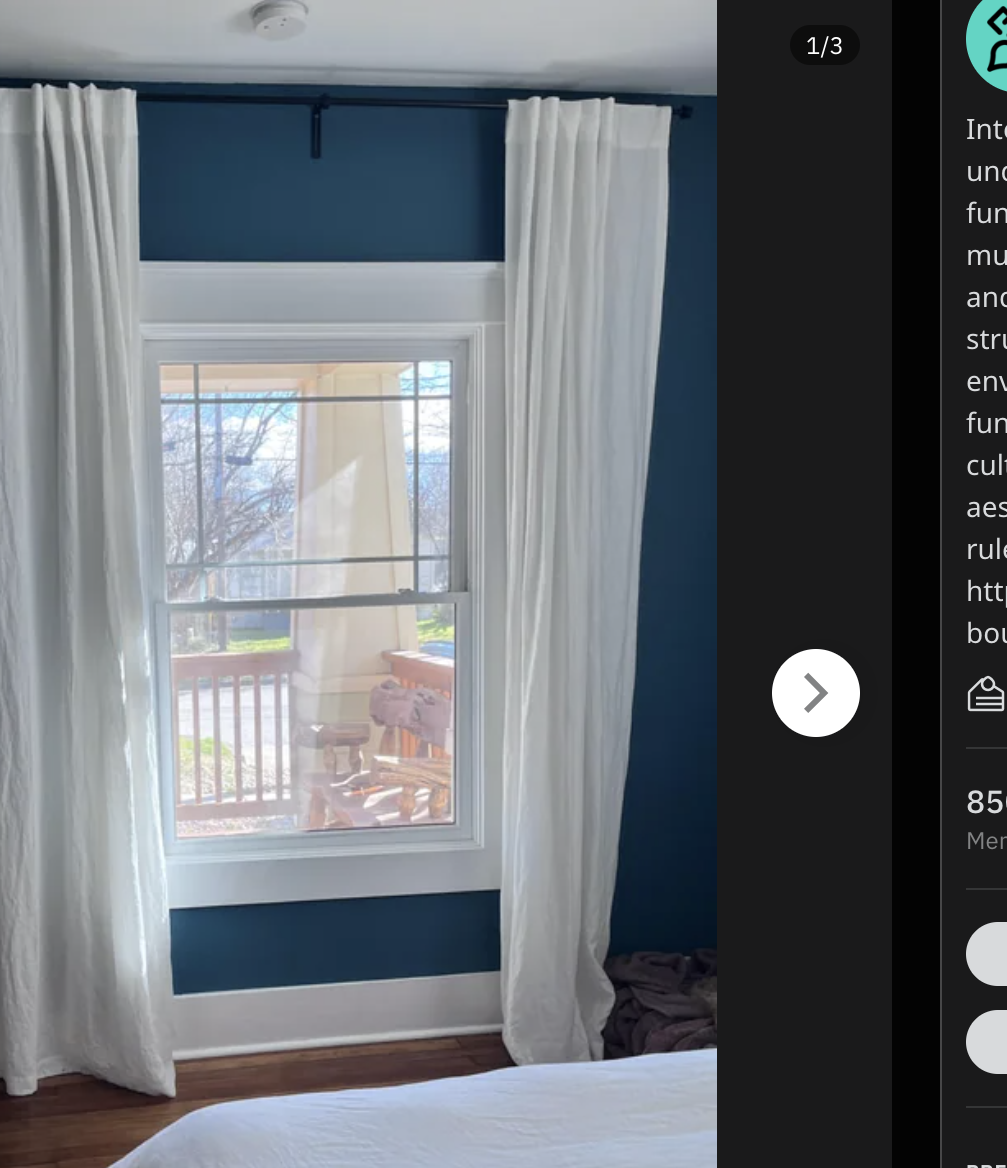 Bedroom with large window, sheer curtains, and a bed facing a wall-mounted TV