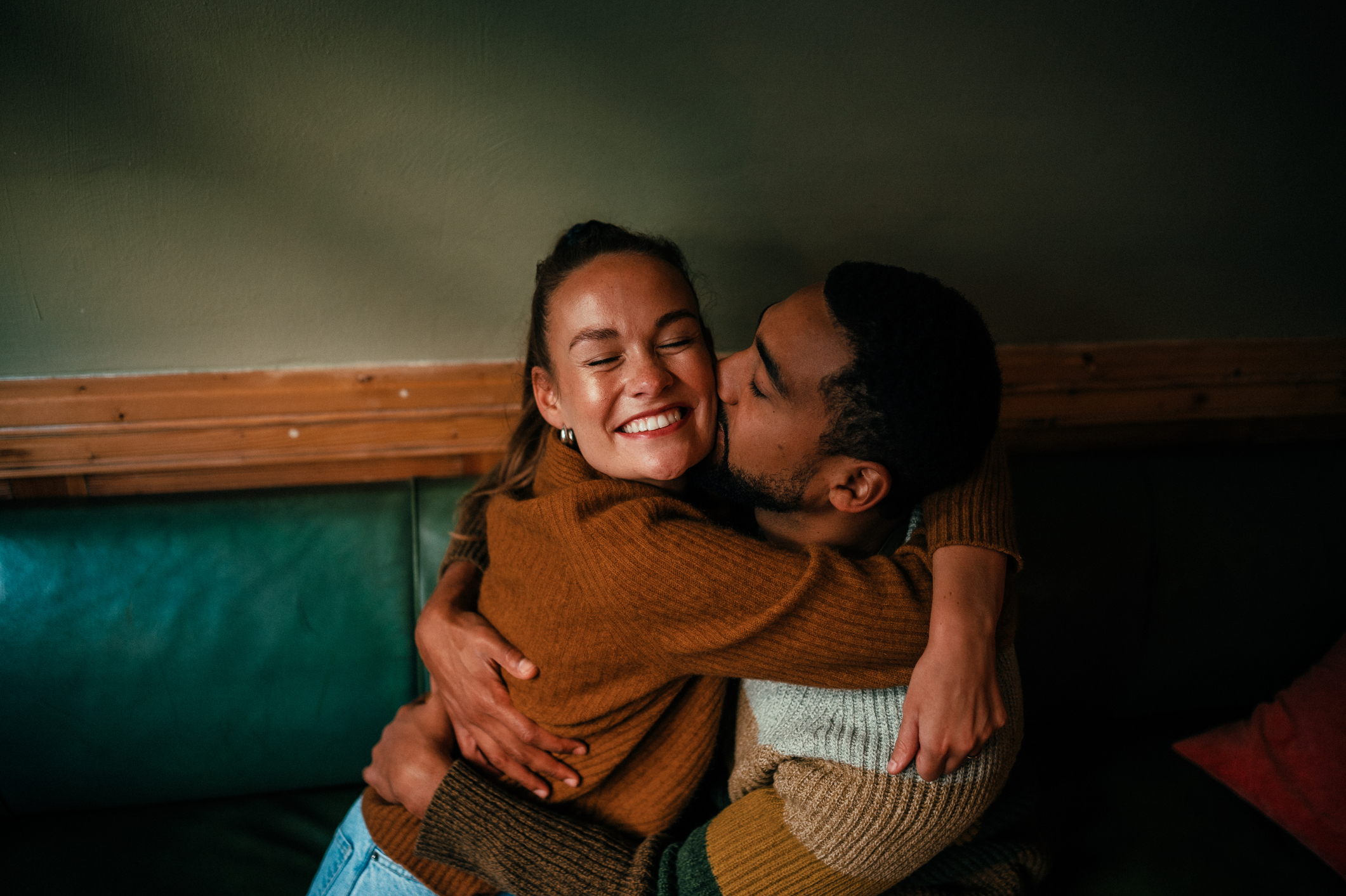 Couple embracing and smiling, man kissing woman on the cheek, expressing affection and love