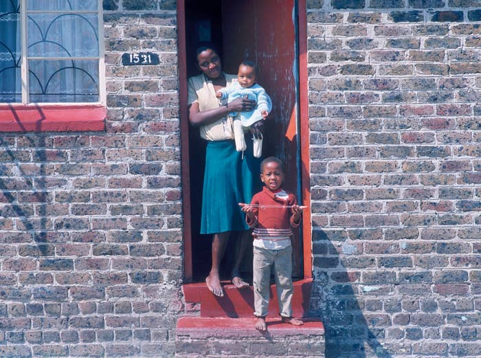 Woman holding a baby and toddler standing at an open doorway