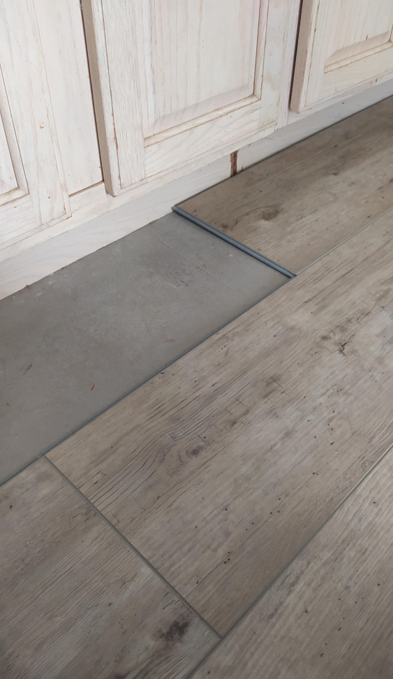 Threshold between a tile and wooden floor, showing a change in texture and level