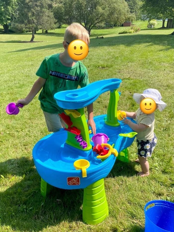 Two children playing with a water table toy outdoors
