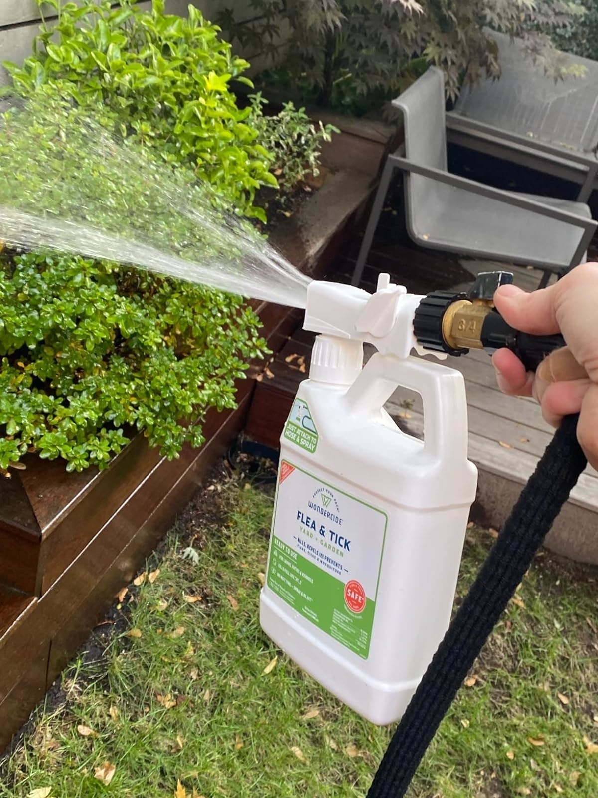 a reviewer spraying their hose with the bottle of spray attached