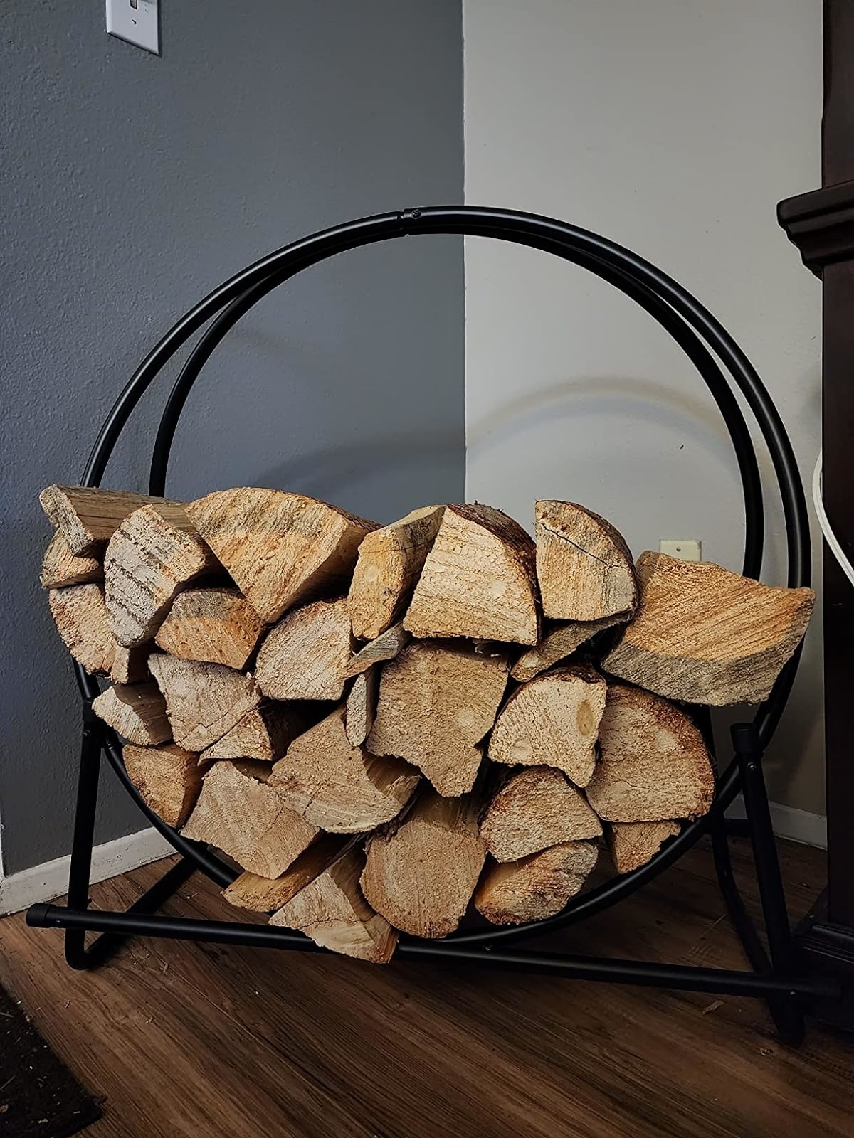 a reviewer&#x27;s circular metal log holder filled with firewood