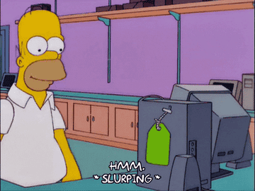 Homer Simpson at a computer, drinking from a green cup with a straw, looking puzzled