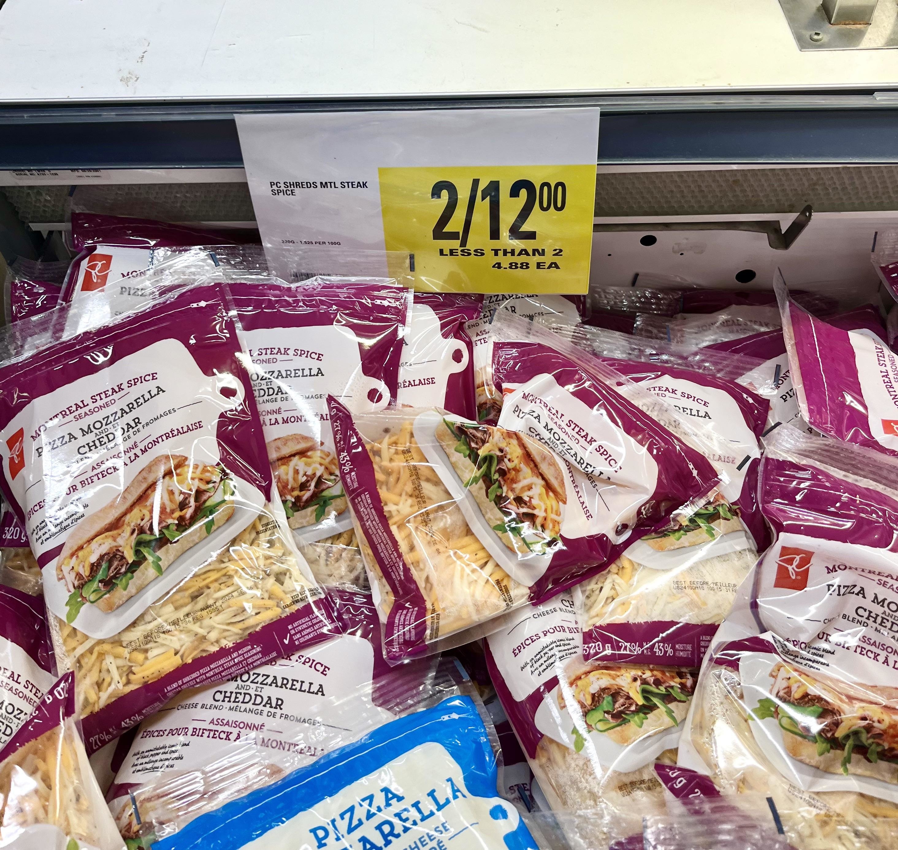 Packages of pizza steak cheese in a store display with a 2 for $12 deal sign above