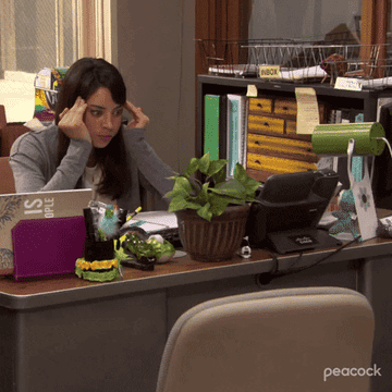 Woman at office desk with hands on temples, expressing frustration or concentration