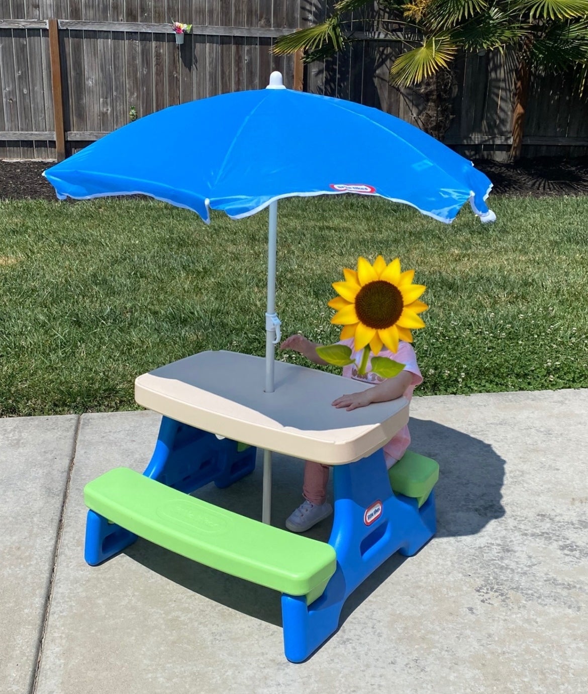 Child seated at a picnic table with an umbrella