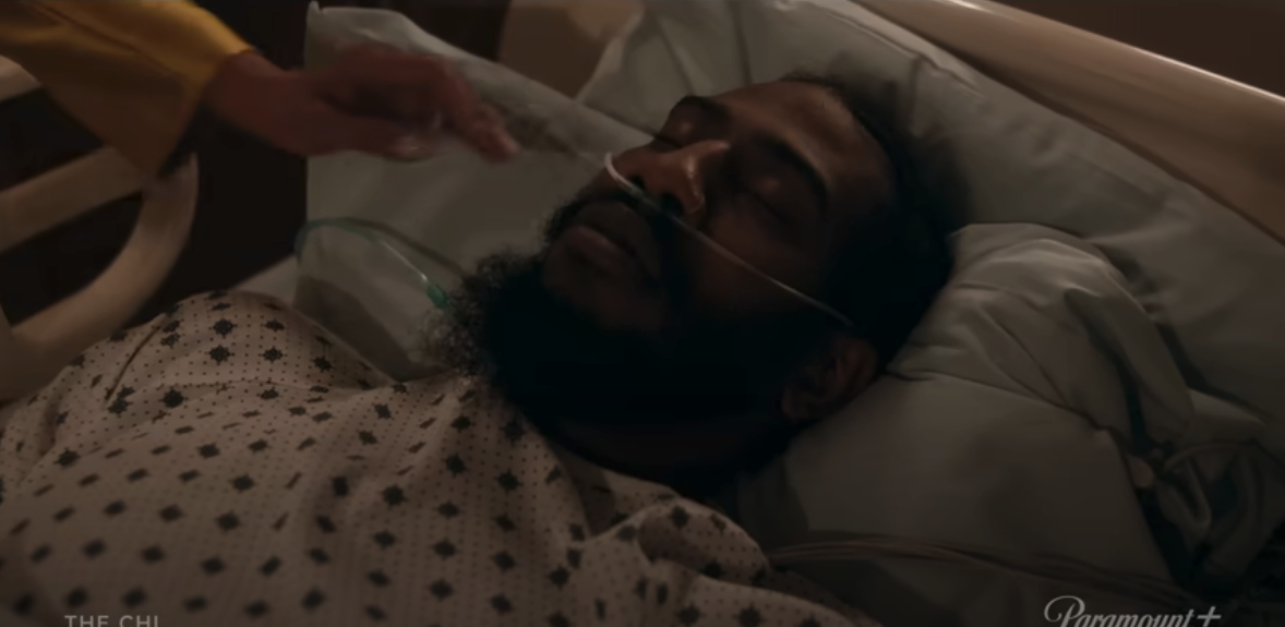 A scene from &quot;The Chi&quot; with a character in a hospital bed, another character reaches out to them