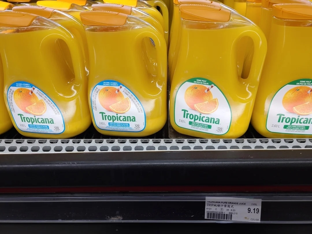 Tropicana orange juice containers on a grocery store shelf with a price tag displayed