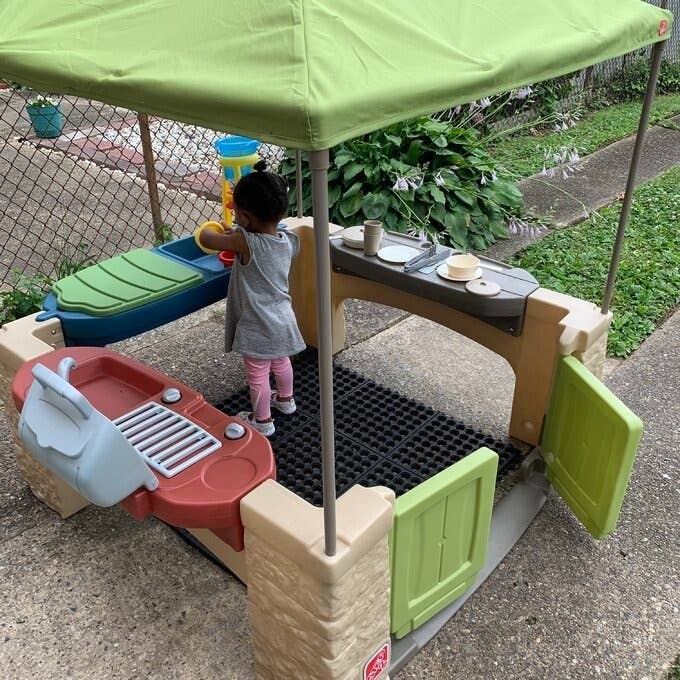 Child playing with an outdoor toy kitchen set