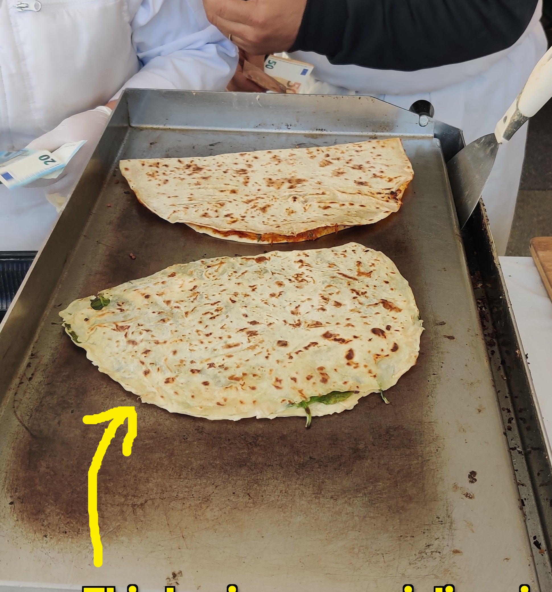 Chefs preparing traditional flatbreads on a hot griddle at a street market