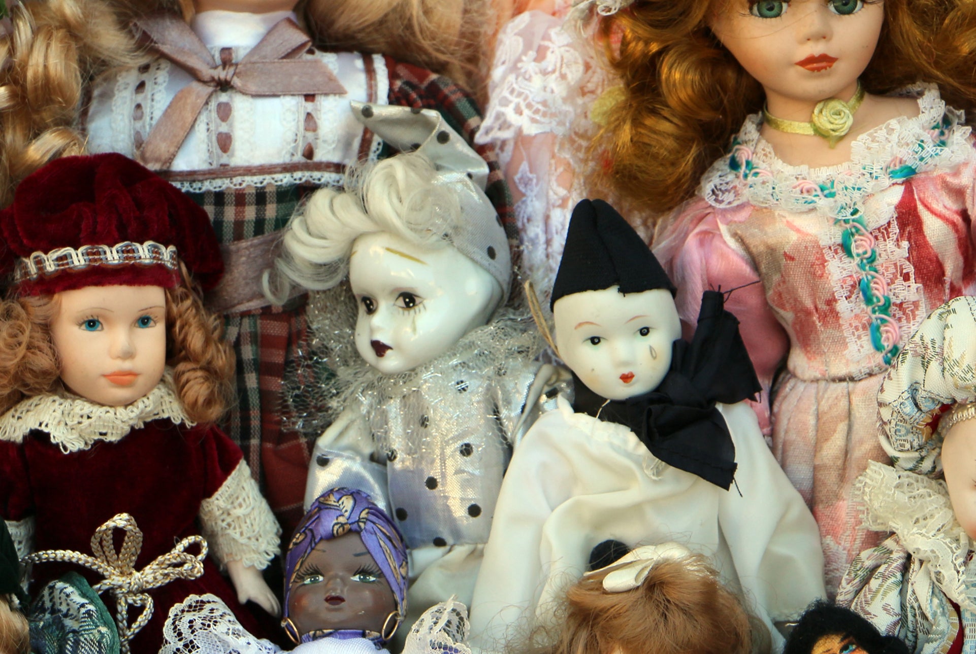 Assorted vintage dolls displayed together, featuring various outfits and expressions