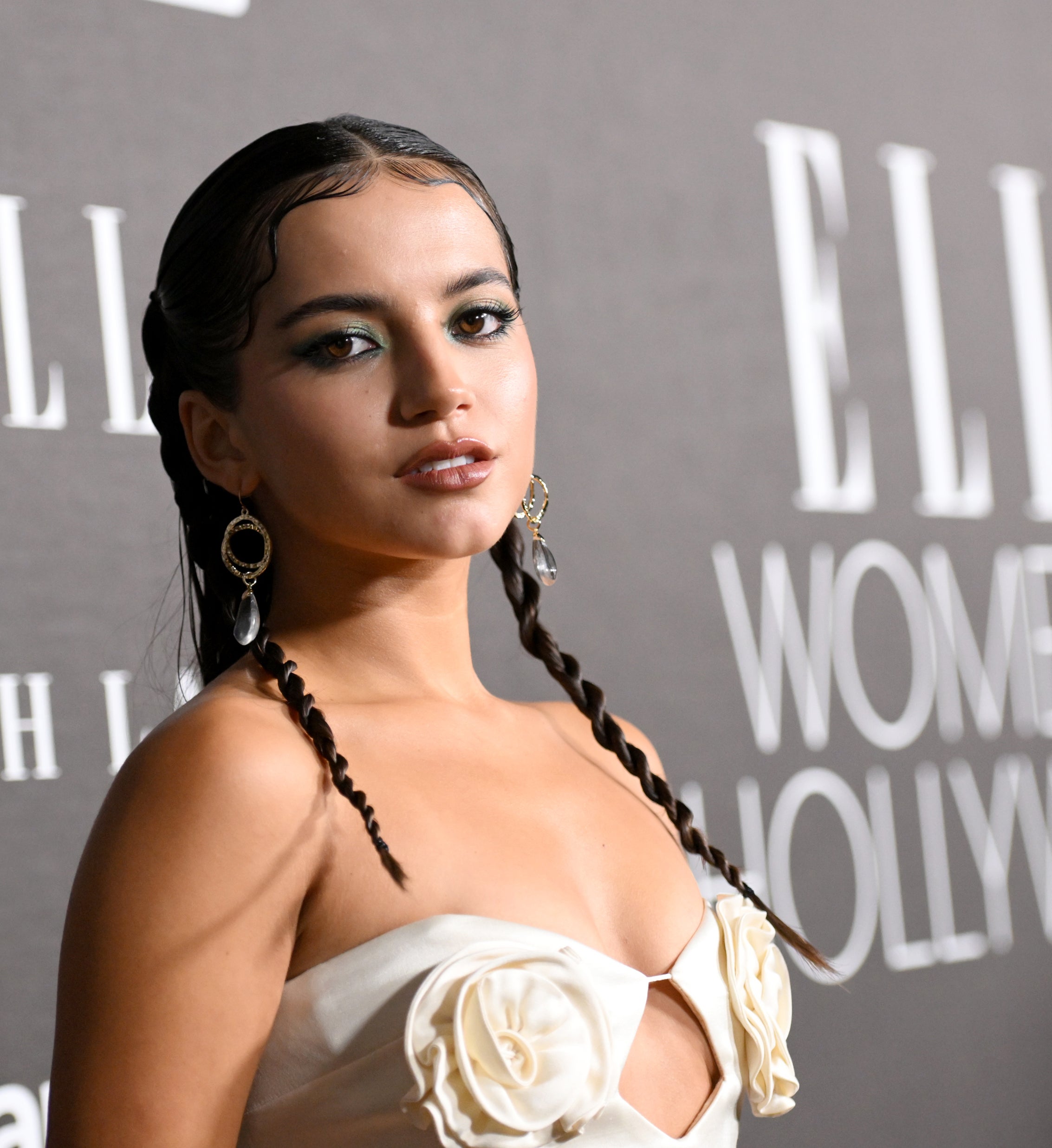 Woman in elegant dress with floral detail poses at an event with &#x27;ELLE Women in Hollywood&#x27; backdrop