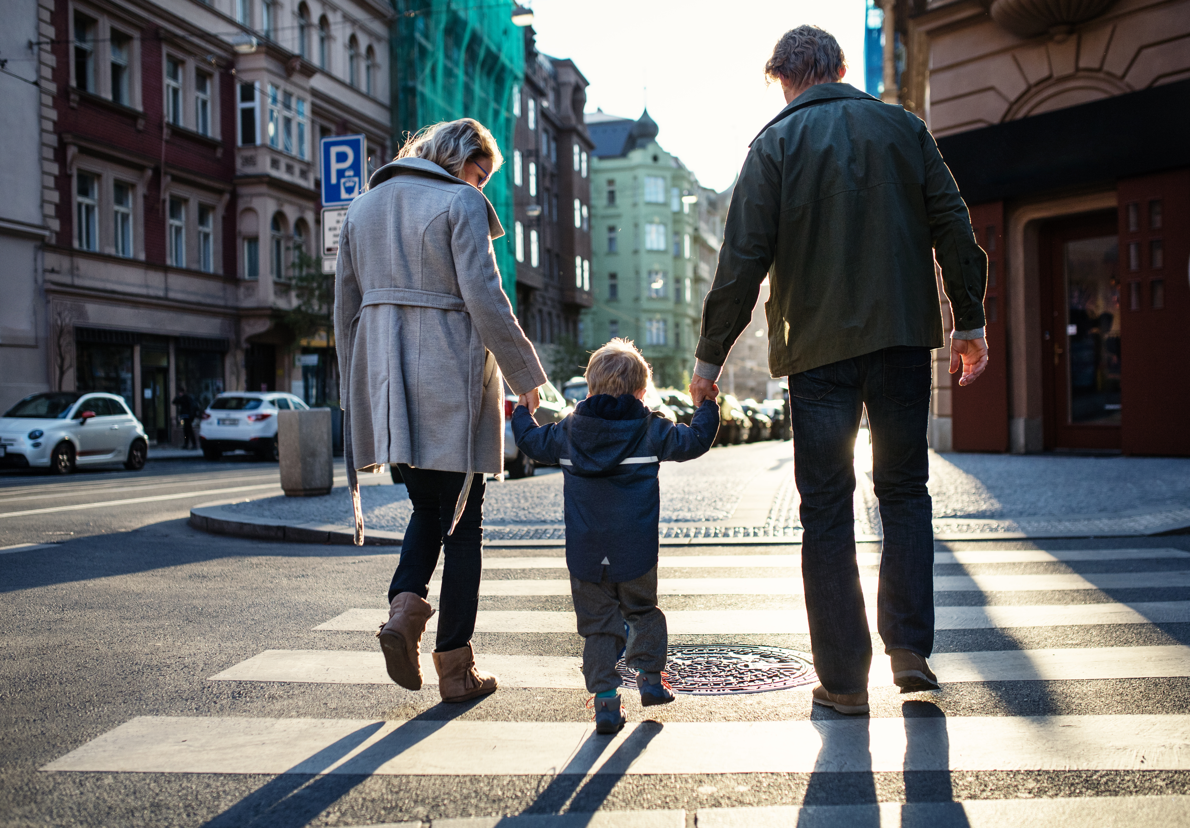 Family with a child holding hands and crossing the street