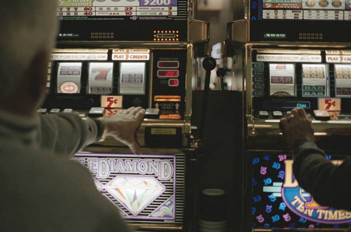 Two people playing slot machines with one labeled &quot;Double Diamond&quot; and the other labeled &quot;Lion Ten Times Pay.&quot;