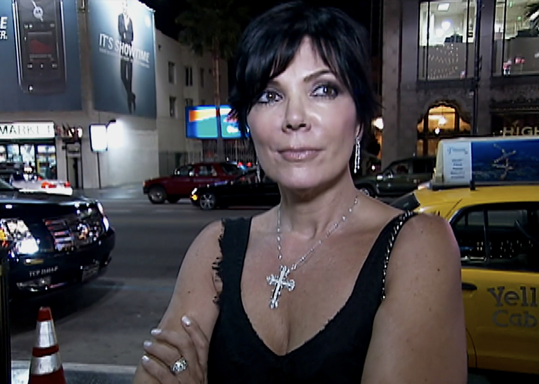 Kris Jenner stands outdoors at night with her arms crossed