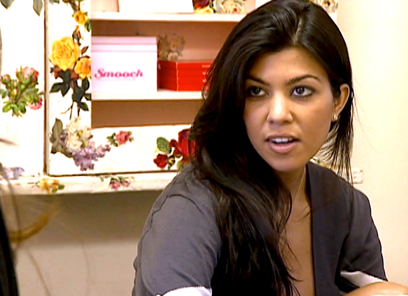 Kourtney Kardashian sitting indoors and engaged in a conversation