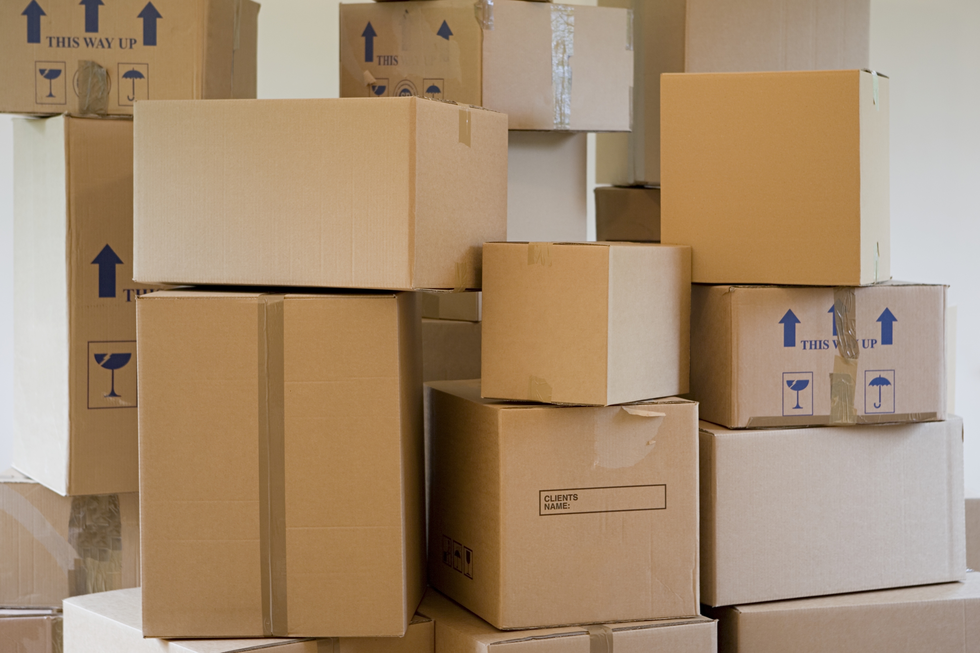 Stacked cardboard moving boxes in various sizes, some labeled with &quot;This way up&quot; and fragile symbols