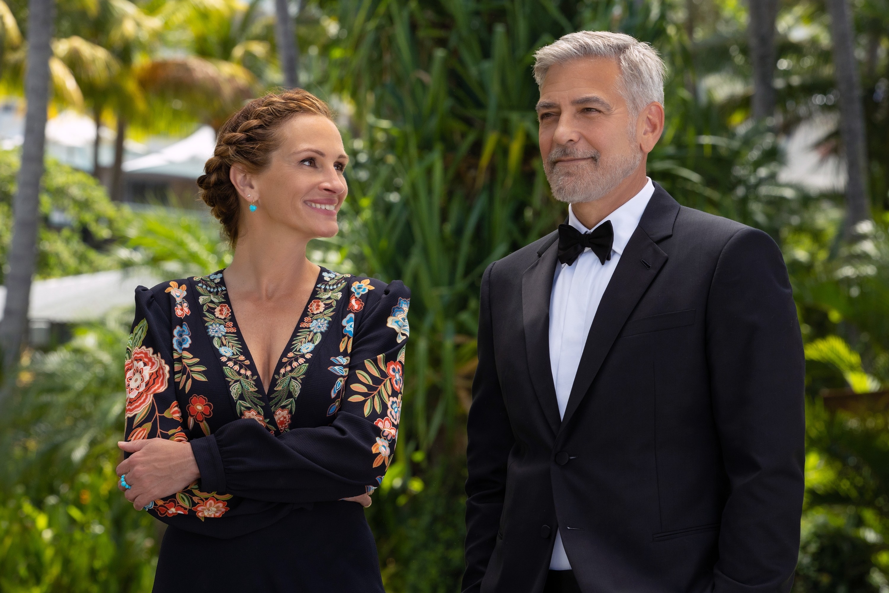 Julia Roberts and George Clooney in formalwear in an outdoor tropical scene from &quot;Ticket to Paradise&quot;