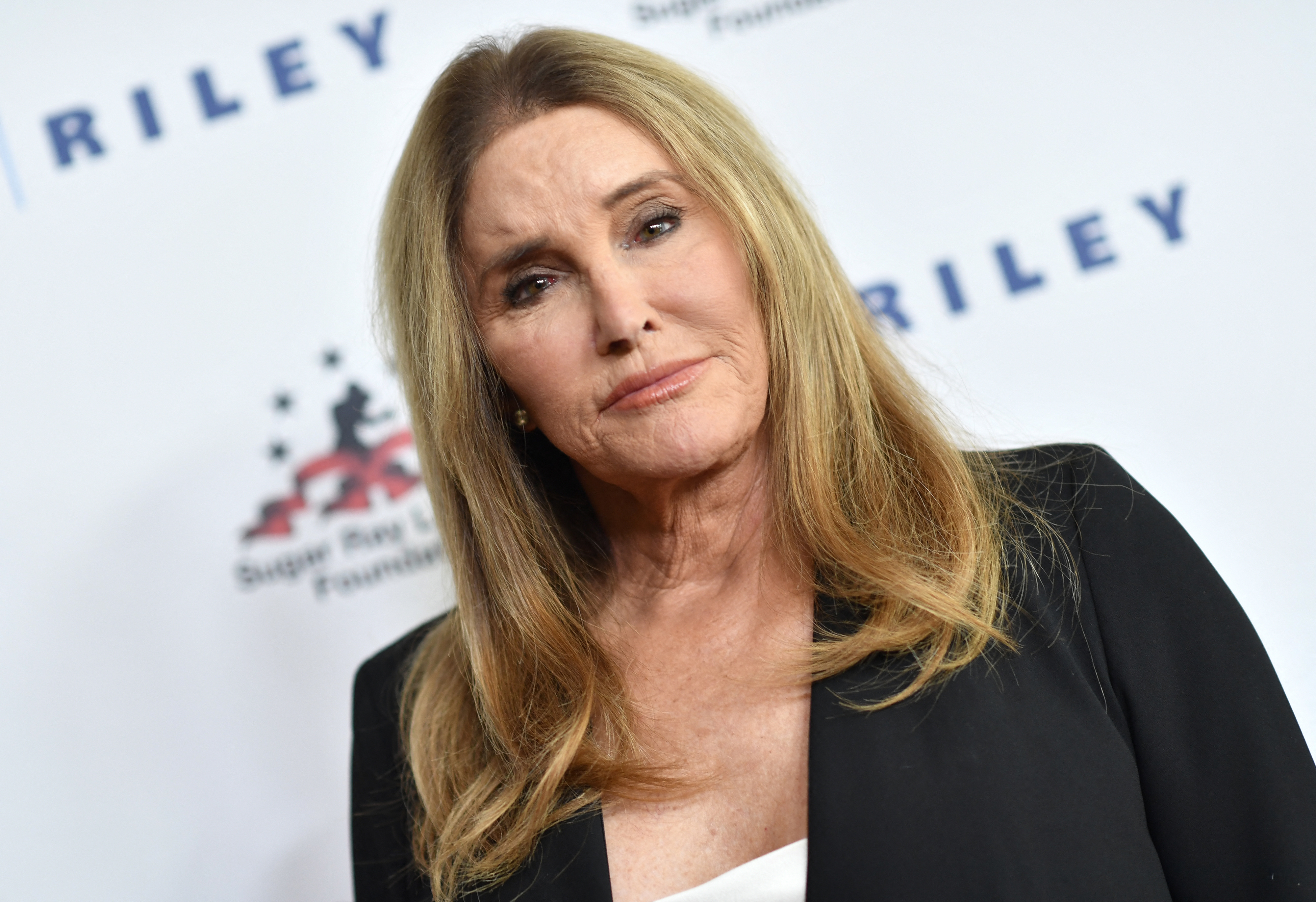 Caitlyn Jenner posing on the red carpet in a black blazer over a white top