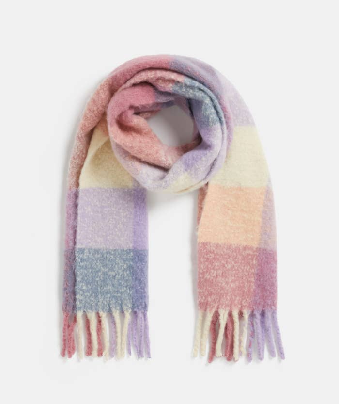 A cozy checkered scarf with mixed pastel hues, featuring fringe detailing along the bottom edge. Item is part of a shopping article
