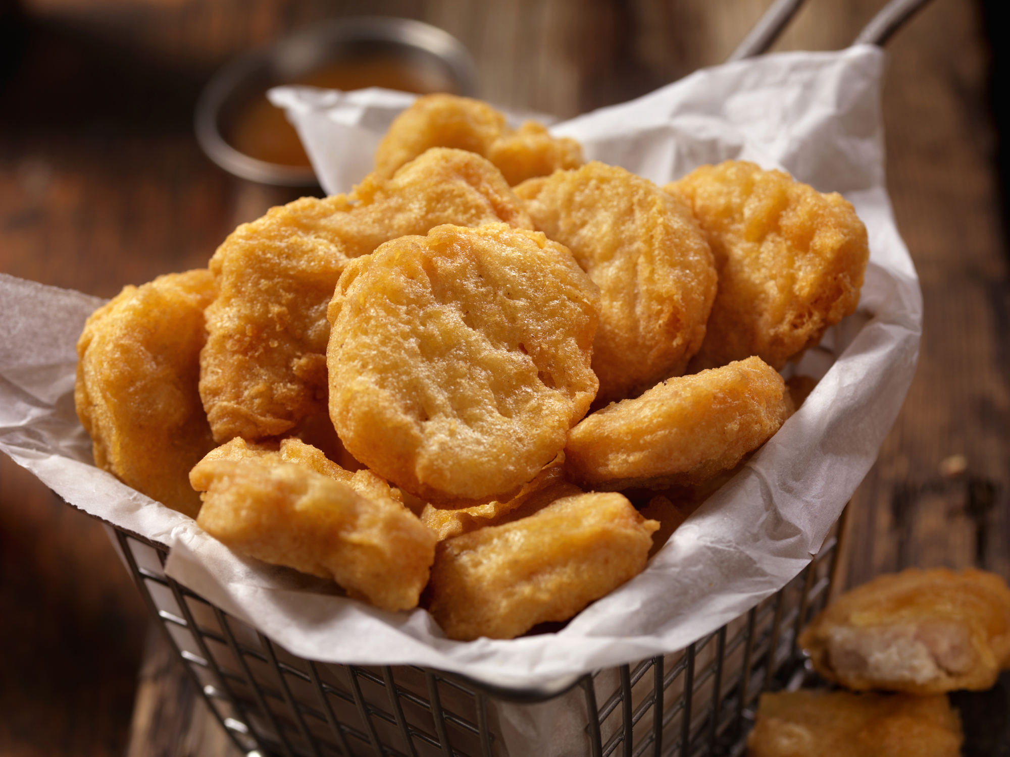 A basket filled with crispy, golden chicken nuggets on a wooden table