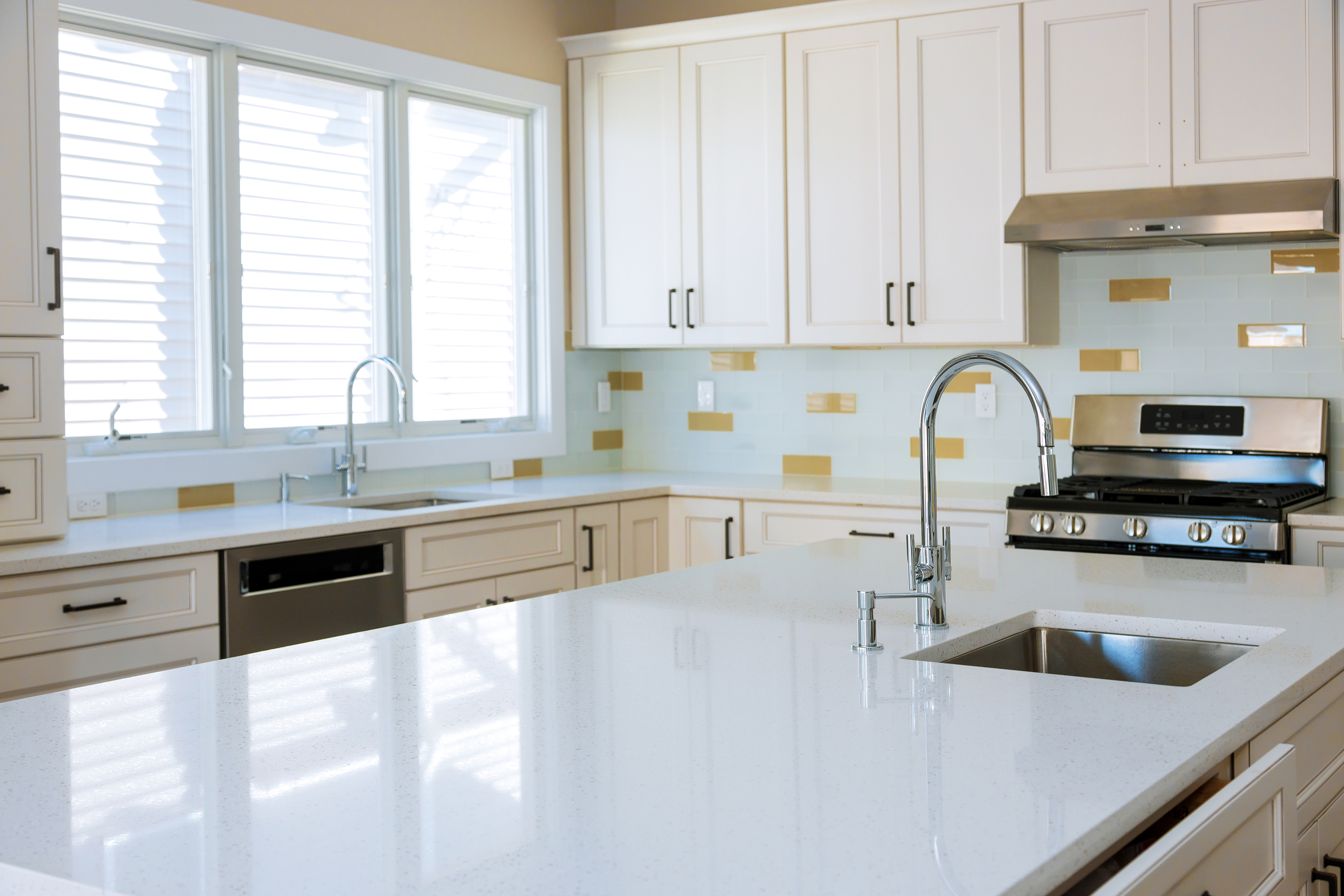 Modern kitchen with white cabinets, stainless steel appliances, a large island with a sink, and tile backsplash